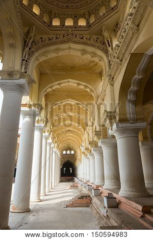 Madurai India - October 21 2013: Shot through a long columned gallery at the Nayak Palace. Succession of yellow domes and white pillars.