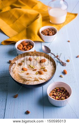 Indian sweet sutarfeni or sutar feni or firni or seviyan or laccha, shredded, flaky-rice-flour roasted in ghee, blended with melted sugar to form a cotton candy, topped with pistachio and almonds