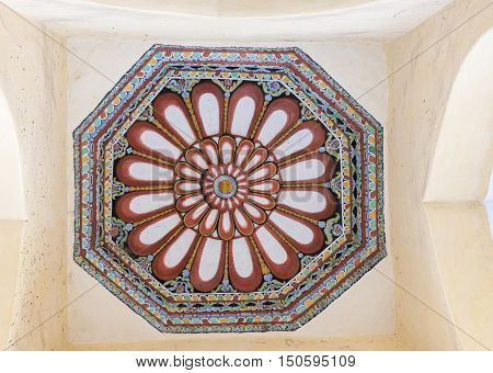 Madurai India - October 21 2013: Shot on the abundant decoration of one octagon ceiling at Nayak Palace. Cream with wine-colored lotus images and green blue yellow backgrounds.