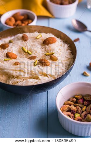 Indian sweet sutarfeni or sutar feni or firni or seviyan or laccha, shredded, flaky-rice-flour roasted in ghee, blended with melted sugar to form a cotton candy, topped with pistachio and almonds