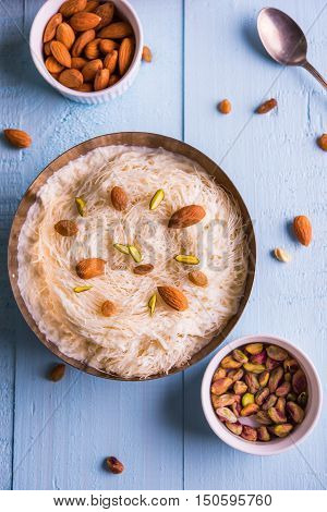 Indian sweet sutarfeni or sutar feni or firni or seviyan or laccha, shredded, flaky-rice-flour roasted in ghee, blended with melted sugar to form a cotton candy, topped with pistachio and almonds