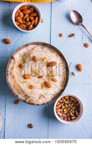 Indian sweet sutarfeni or sutar feni or firni or seviyan or laccha, shredded, flaky-rice-flour roasted in ghee, blended with melted sugar to form a cotton candy, topped with pistachio and almonds
