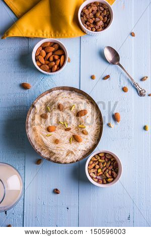 Indian sweet sutarfeni or sutar feni or firni or seviyan or laccha, shredded, flaky-rice-flour roasted in ghee, blended with melted sugar to form a cotton candy, topped with pistachio and almonds