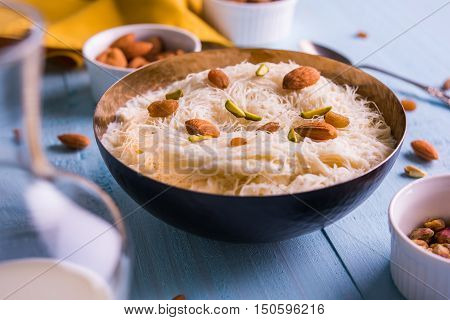 Indian sweet sutarfeni or sutar feni or firni or seviyan or laccha, shredded, flaky-rice-flour roasted in ghee, blended with melted sugar to form a cotton candy, topped with pistachio and almonds