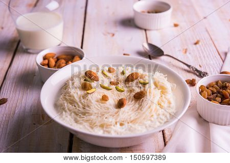 Indian sweet sutarfeni or sutar feni or firni or seviyan or laccha, shredded, flaky-rice-flour roasted in ghee, blended with melted sugar to form a cotton candy, topped with pistachio and almonds