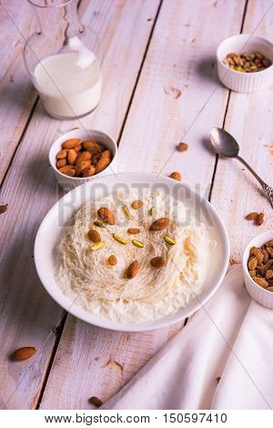 Indian sweet sutarfeni or sutar feni or firni or seviyan or laccha, shredded, flaky-rice-flour roasted in ghee, blended with melted sugar to form a cotton candy, topped with pistachio and almonds