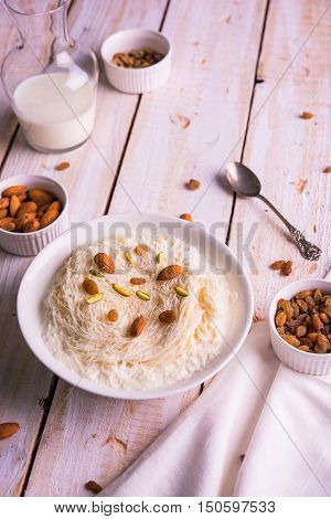 Indian sweet sutarfeni or sutar feni or firni or seviyan or laccha, shredded, flaky-rice-flour roasted in ghee, blended with melted sugar to form a cotton candy, topped with pistachio and almonds