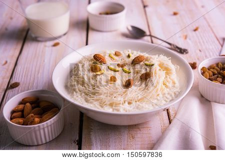 Indian sweet sutarfeni or sutar feni or firni or seviyan or laccha, shredded, flaky-rice-flour roasted in ghee, blended with melted sugar to form a cotton candy, topped with pistachio and almonds