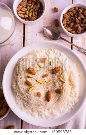 Indian sweet sutarfeni or sutar feni or firni or seviyan or laccha, shredded, flaky-rice-flour roasted in ghee, blended with melted sugar to form a cotton candy, topped with pistachio and almonds