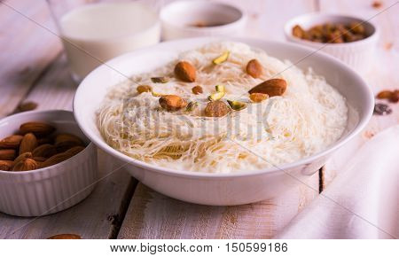 Indian sweet sutarfeni or sutar feni or firni or seviyan or laccha, shredded, flaky-rice-flour roasted in ghee, blended with melted sugar to form a cotton candy, topped with pistachio and almonds