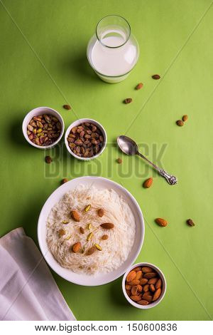 Indian sweet sutarfeni or sutar feni or firni or seviyan or laccha, shredded, flaky-rice-flour roasted in ghee, blended with melted sugar to form a cotton candy, topped with pistachio and almonds
