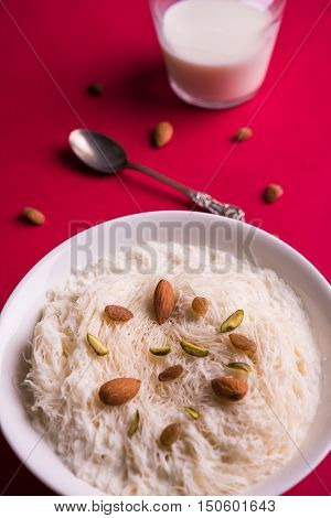 Indian sweet sutarfeni or sutar feni or firni or seviyan or laccha, shredded, flaky-rice-flour roasted in ghee, blended with melted sugar to form a cotton candy, topped with pistachio and almonds