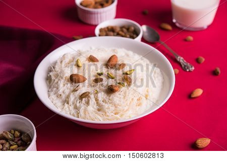 Indian sweet sutarfeni or sutar feni or firni or seviyan or laccha, shredded, flaky-rice-flour roasted in ghee, blended with melted sugar to form a cotton candy, topped with pistachio and almonds