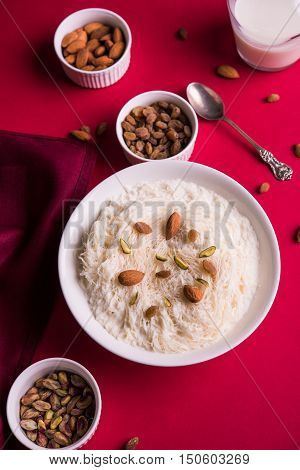 Indian sweet sutarfeni or sutar feni or firni or seviyan or laccha, shredded, flaky-rice-flour roasted in ghee, blended with melted sugar to form a cotton candy, topped with pistachio and almonds