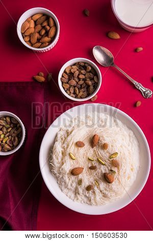 Indian sweet sutarfeni or sutar feni or firni or seviyan or laccha, shredded, flaky-rice-flour roasted in ghee, blended with melted sugar to form a cotton candy, topped with pistachio and almonds