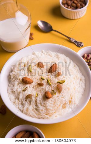 Indian sweet sutarfeni or sutar feni or firni or seviyan or laccha, shredded, flaky-rice-flour roasted in ghee, blended with melted sugar to form a cotton candy, topped with pistachio and almonds