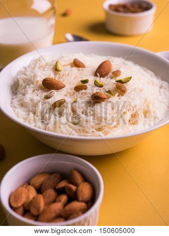 Indian sweet sutarfeni or sutar feni or firni or seviyan or laccha, shredded, flaky-rice-flour roasted in ghee, blended with melted sugar to form a cotton candy, topped with pistachio and almonds