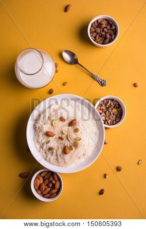 Indian sweet sutarfeni or sutar feni or firni or seviyan or laccha, shredded, flaky-rice-flour roasted in ghee, blended with melted sugar to form a cotton candy, topped with pistachio and almonds