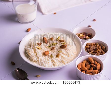 Indian sweet sutarfeni or sutar feni or firni or seviyan or laccha, shredded, flaky-rice-flour roasted in ghee, blended with melted sugar to form a cotton candy, topped with pistachio and almonds
