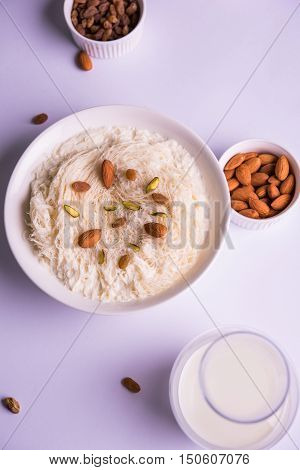 Indian sweet sutarfeni or sutar feni or firni or seviyan or laccha, shredded, flaky-rice-flour roasted in ghee, blended with melted sugar to form a cotton candy, topped with pistachio and almonds
