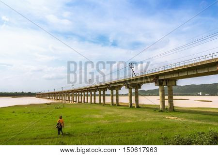 Bridge of train railway cross grass field meadow and river at Pasak River Dam Lopburi Unseen in Thailand.