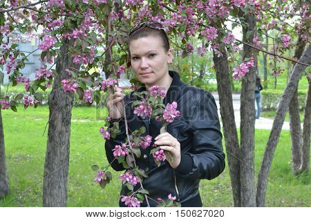 Young girl in glasses standing near blooming apple tree thoughtfully looks ahead