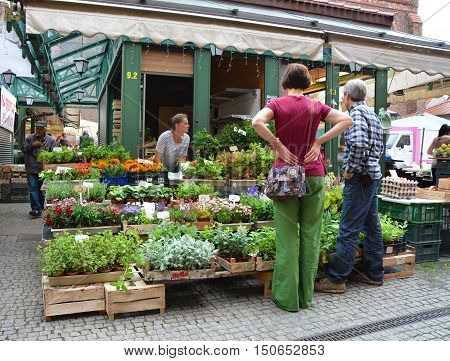 GDANSK POLAND - JUNE 27 2015: People shop at the herbs and flowers stall market in old town. Gdansk has one of the largest seaports on the Baltic Sea