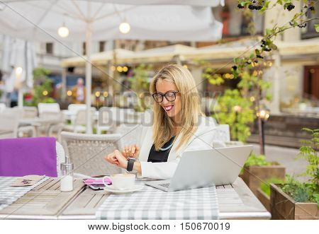 Woman sitting in cafe and using digital touch screen watch