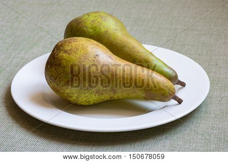 Two green fresh organic pears on white plate
