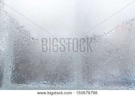 Window. The lower part of the window is covered with water droplets and is visible the window frame. The upper part of the window glass weeping and opaque.