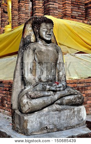 Lamphun Thailand - December 28 2012: A stone Buddha figure seated in Lotus position at the base of the Suwanna Chedi at Wat Phra That Haripunchai Maha Viham