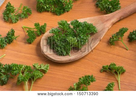 Parsley into a spoon over a wooden table