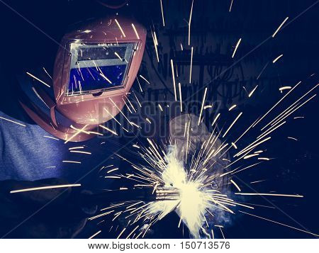 Welder working a welding steel with protective mask and sparks.