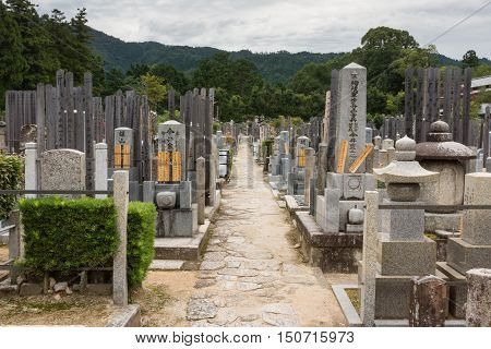 Kyoto Japan - September 15 2016: Adjacent to the Shinnyo-do Buddhist Temple is a large cemetery serving the Buddhist community. Long alley with the classic Japanese tombstones leads to the woods. Mountains in the back.