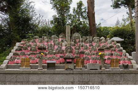 Kyoto Japan - September 15 2016: At the Shinnyo-do Buddhist Temple a collection of small tombstones for children is set together each with a red apron or Rakusu. The fabric protects the dead children in the afterlife.
