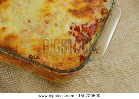 Close up oif Baked casserole with melted cheese, marina sauce, chicken and mixed vegetables on rotini pasta in glass baking dish
