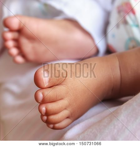 A newborn baby feet against a white blanket.