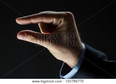 business, people, sign language and gesture concept - close up of businessman hand showing small size over black background