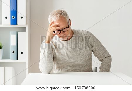 old age, problem, health care and people concept - sad senior man sitting at table at medical office