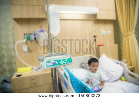 Blur Illness asian boy sitting on sickbed in hospital with infusion pump intravenous IV drip.
