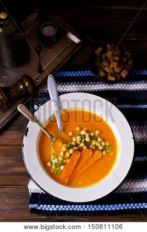 Pumpkin and carrot soup with chickpeas on a dark background. Selective focus.