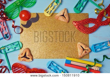 Purim golden glitter background with carnival mask party costume and hamantaschen cookies. View from above