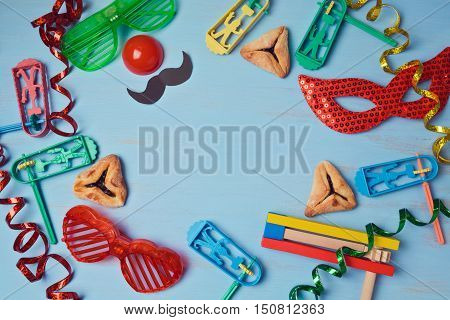 Purim background with carnival mask party costume and hamantaschen cookies. View from above