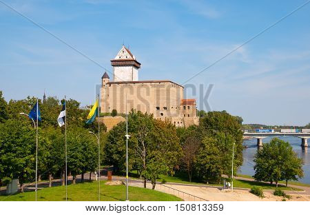 NARVA, ESTONIA - AUGUST 21, 2016: Hermann Castle (Hermannsfeste) on the bank of The Narva (Narova) River. On the right side is The Bridge of Friendship between Estonia and Russian Federation