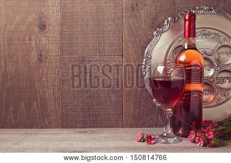 Passover celebration with wine and seder plate over wooden background