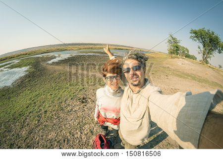 Couple taking selfie on Chobe River Namibia Botswana border Africa. Fisheye view from above toned image. Chobe National Park famous wildlilfe reserve and upscale travel destination.