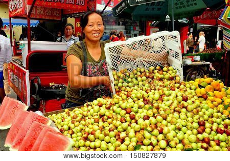 Pengzhou China - October 2 2013: Woman selling Chinese dates and watermelon slices from the back of her pickup truck at the Long Xing outdoor marketplace