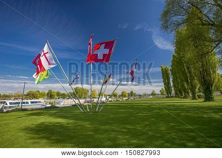 Swiss and cantonal flags in the centre of park in Kreuzlingen with the lake Constance in the background Switzerland.