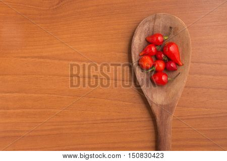 Biquinho Pepper into a spoon. Capsicum Chinense over a wooden table