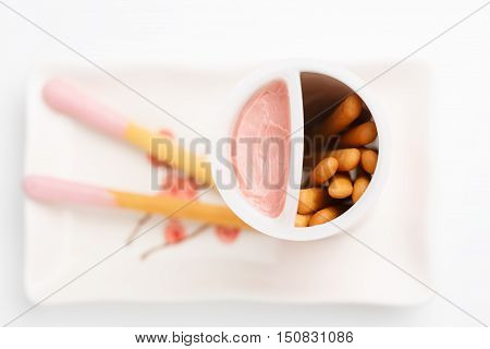 Biscuit cookie sticks with pink friut cream on rectangular plate with flower pattern isolated on white background